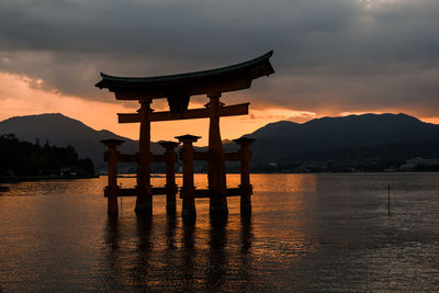 Silhouette japanese temple gates floating torii against sky during sunset