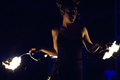 Woman holding burning ring while performing at night