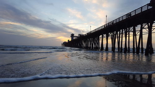 Pier over sea against sky during sunset