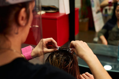 A close-up of a hairdresser combing a client with a face shield