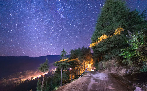 Road amidst trees against sky at night