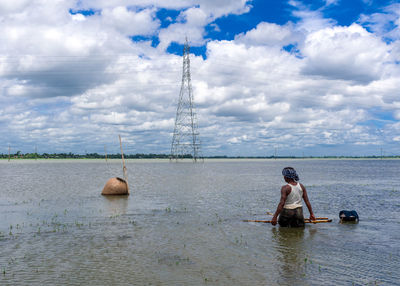 Rear view of woman standing in sea against sky