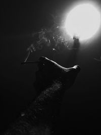 Close-up of man smoking cigarette against black background