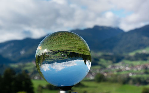 Close-up of glass ball against sky