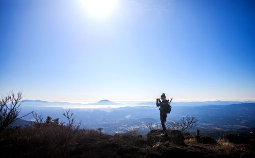 Man standing on mountain against blue sky