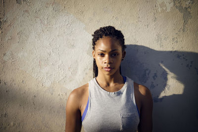 Portrait of confident woman standing against wall