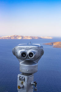 Close-up of coin-operated binoculars by sea against sky