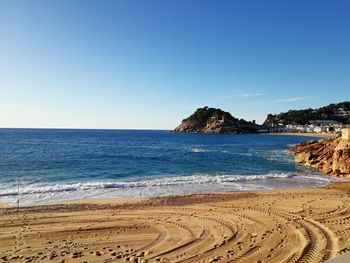 Scenic view of beach against clear blue sky