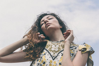 Low angle view of woman looking at camera against sky