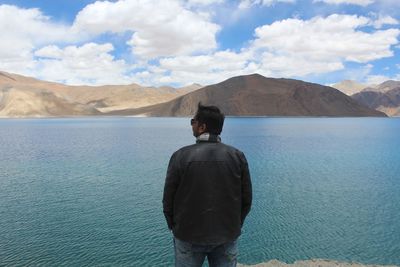 Rear view of man looking at mountains against sky