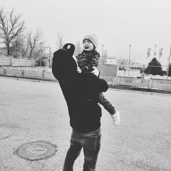 Rear view of man photographing woman against sky