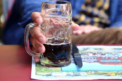 Close-up of hand holding drink on table