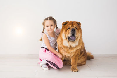 Portrait of girl with dog sitting on floor