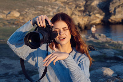 Portrait of smiling young woman photographing camera