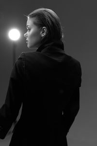 Side view of woman standing against gray background