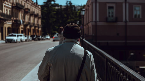 Rear view of man walking on street against buildings in city