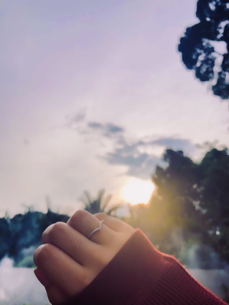 CLOSE-UP OF HAND HOLDING SUN AGAINST SKY