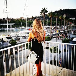 Rear view of woman standing in balcony against harbor