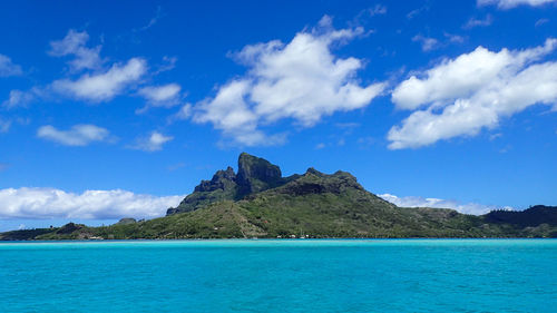 Scenic view of sea and mountains against blue sky