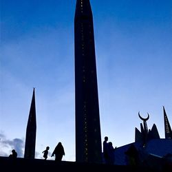 Low angle view of people walking against blue sky