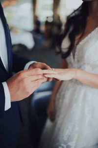 Midsection of man putting ring on bride finger during wedding ceremony 