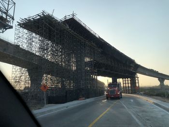 Cars on bridge against sky in city