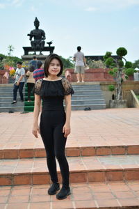 Full length portrait of woman standing against sky