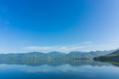 Scenic view of lake by mountains against blue sky