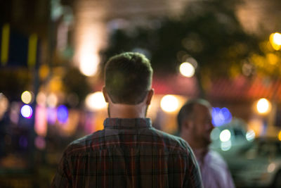 Rear view of man with illuminated lights at night