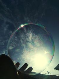 Person holding bubble bubbles against sky