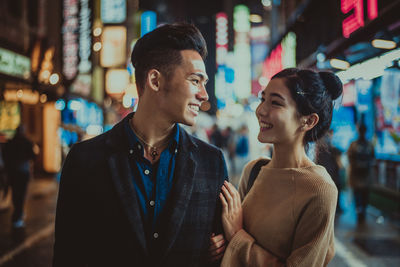 Friends standing at store in city at night