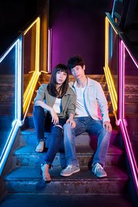 Full length of young couple sitting outdoors