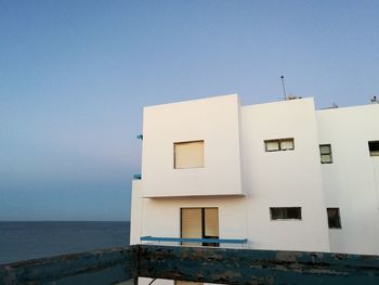 Building by sea against clear blue sky