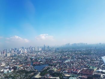 High angle view of city buildings against blue sky