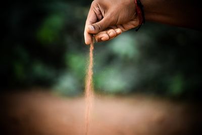 Cropped hand spilling sand outdoors