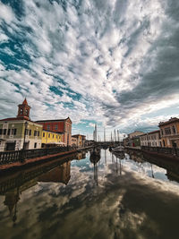 Bridge over river by buildings against sky