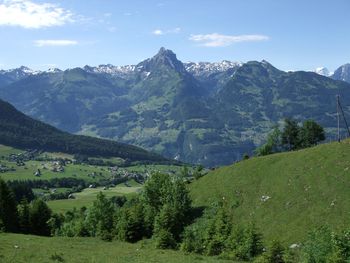 Scenic view of green landscape and mountains against sky