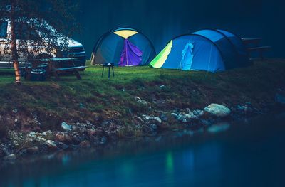 Tents by lake in forest during dusk