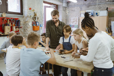 Male teacher with group of pupils working on robotics project at technology workshop in school