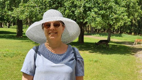 Portrait of woman standing by tree on field