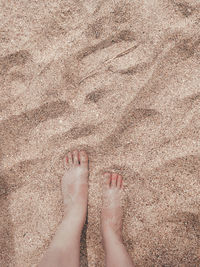 Low section of person standing on sand at beach