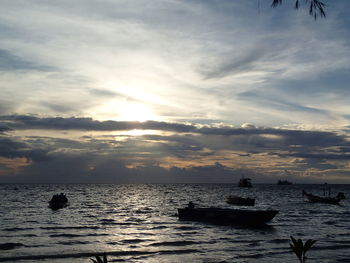 Boats in sea against cloudy sky