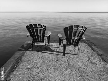 Empty chairs on beach against sky