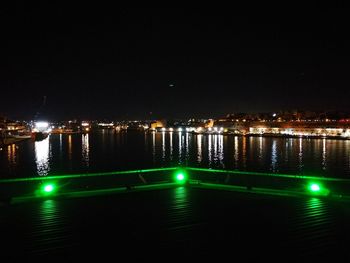 Illuminated swimming pool in city against sky at night