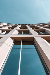 View looking up at building with tap windows against blue sky