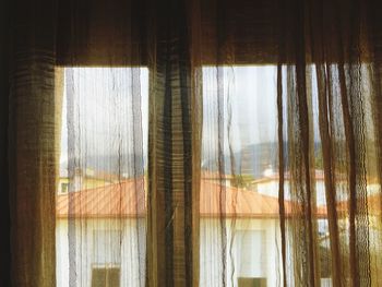 Close-up of curtain against sky seen through window