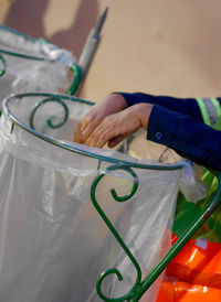 Cropped image of sanitation worker with plastic bag on metallic structure
