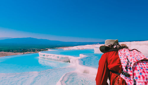 Woman standing on shore against clear blue sky