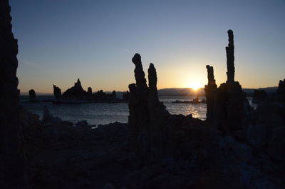 Silhouette rock formation by mono lake against sky during sunset