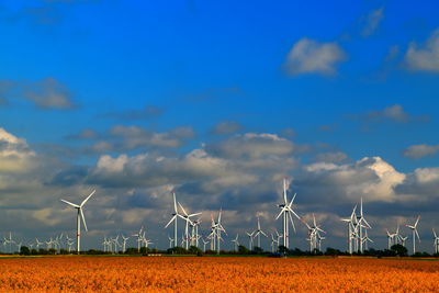 Wind turbines on field against sky with a lot of windmills in line at the horizon